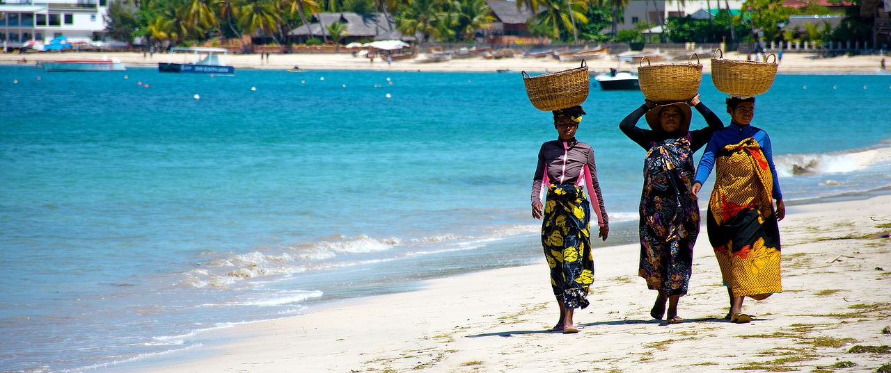 Three Malagasy women walk along the beach